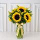 florero con girasoles en florero de cristal, decorado con follajes verdes 